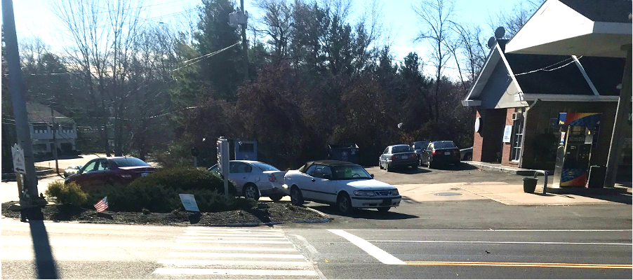 Figure 11 - View across Great Road (Route 117) of Southwest Intersection Corner. Image shows a crosswalk leading to a bed of mulch and vegetation at the perimeter of the gas station parking lot.